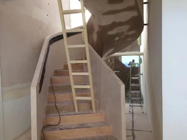 Staircase with the curved wall and the soffit above it skimmed out in one run