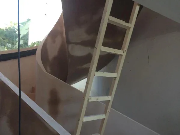 Curved stair soffit skimmed underneath, the ladder still against it