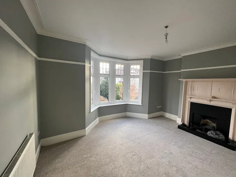 The same room from the door, paint on and carpet down, the walls flat in the window light