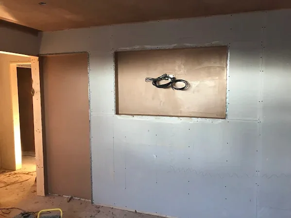 Boarded media wall with the cables left out of the recess ready for the screen