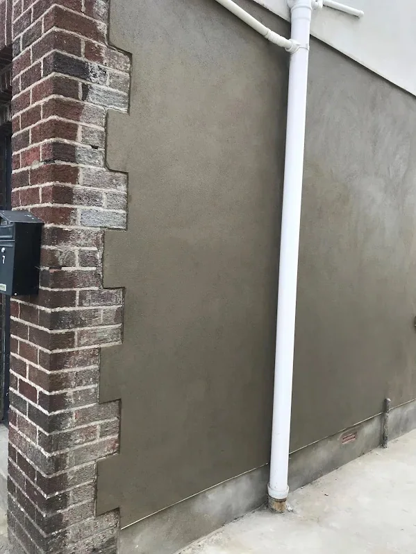 Render finished hard against an exposed brick quoin, the join cut straight down
