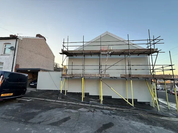 Corner property rendered and scaffolded, from the road at the end of the day