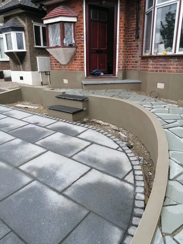 Curved garden retaining wall rendered smooth above a new paved terrace