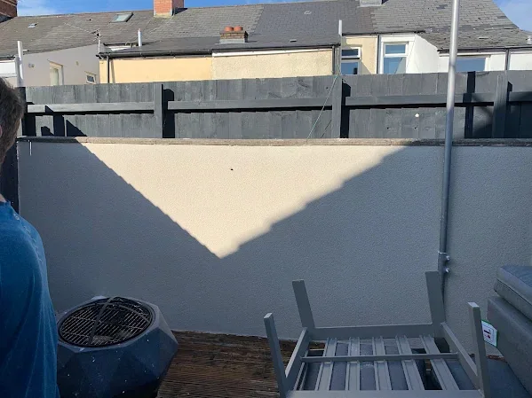 Garden boundary wall rendered flat above a paved back terrace