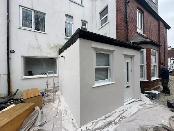 Back elevation and flat-roofed extension re-rendered white, sheets still down