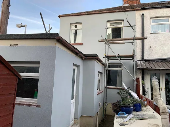 Rear of a semi rendered white, scaffold still standing over the single-storey extension