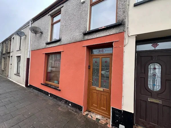 Terraced front rendered and finished in a strong colour beside its neighbours