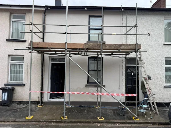 Terraced front rendered white, scaffold up and the path taped off