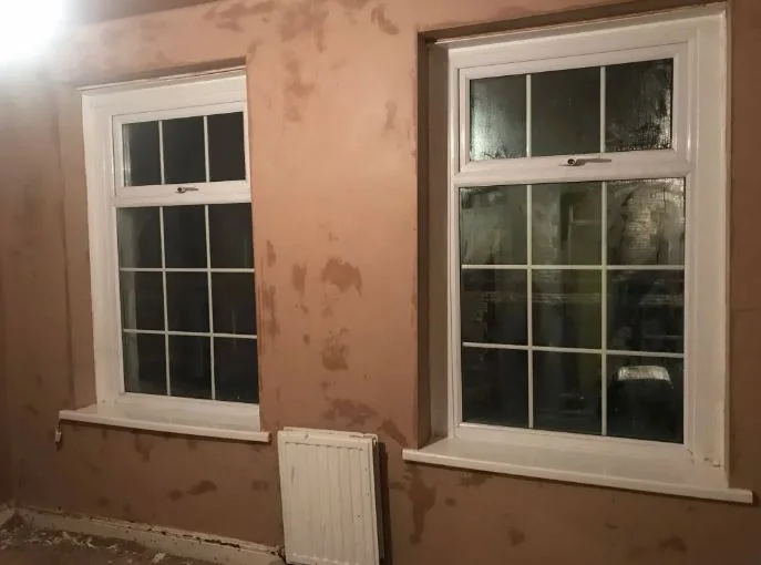 Before: a bay window room stripped back, old finish off the walls