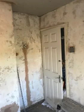 Before: a hallway hacked back to the substrate ready for re-plastering